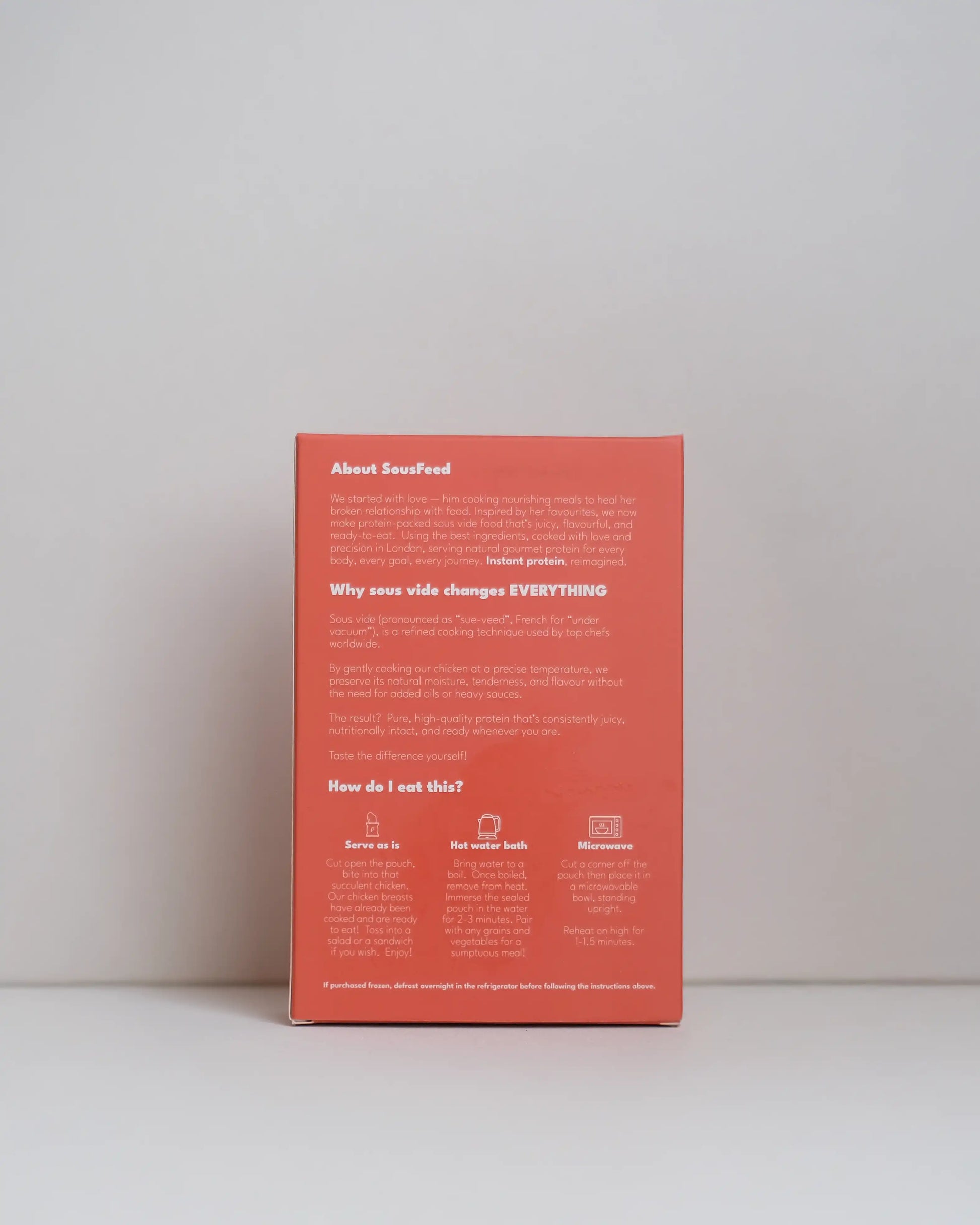 Back view of a SousFeed smoked harissa flavoured chicken breast and its red packaging on a white background