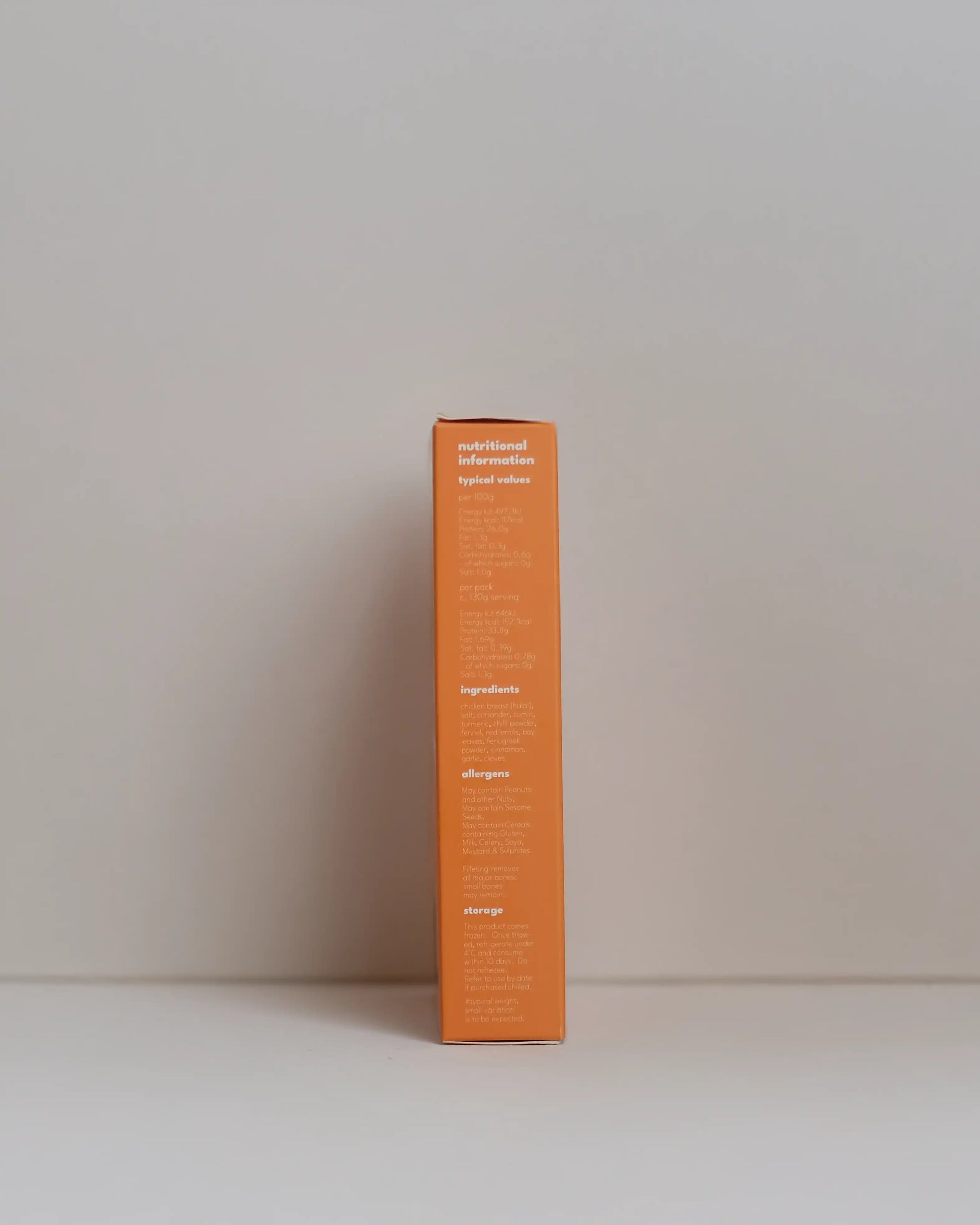 Side view of a SousFeed madras curry flavoured chicken breast and its packaging on a white background
