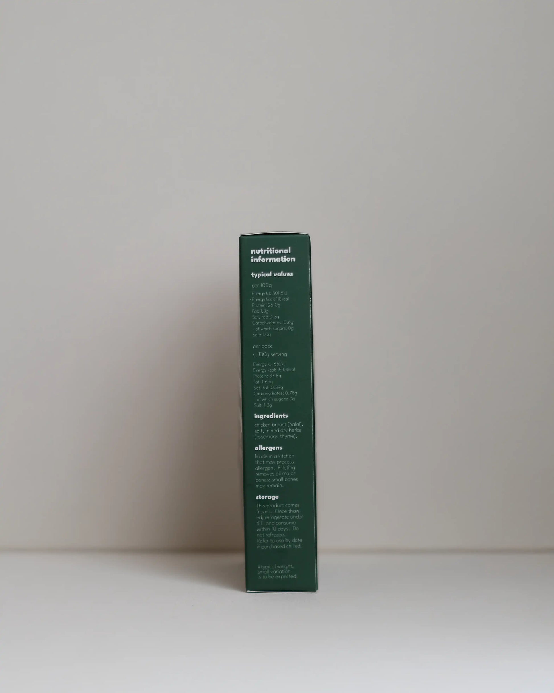Side view of a SousFeed mediterranean herbs flavoured chicken breast and its packaging on a white background