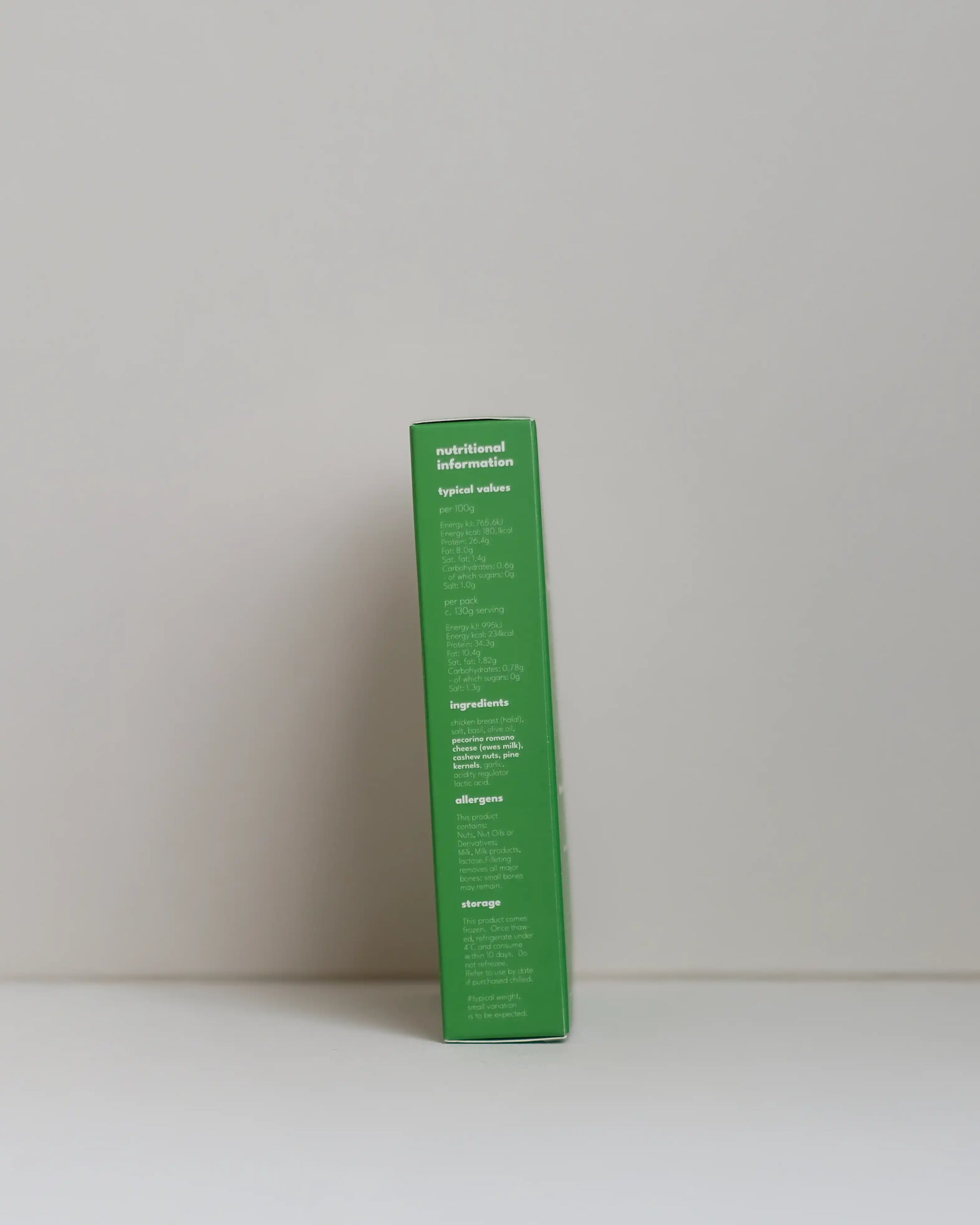 Side view of a SousFeed pesto alla genovese flavoured chicken breast and its light green packaging on a white background
