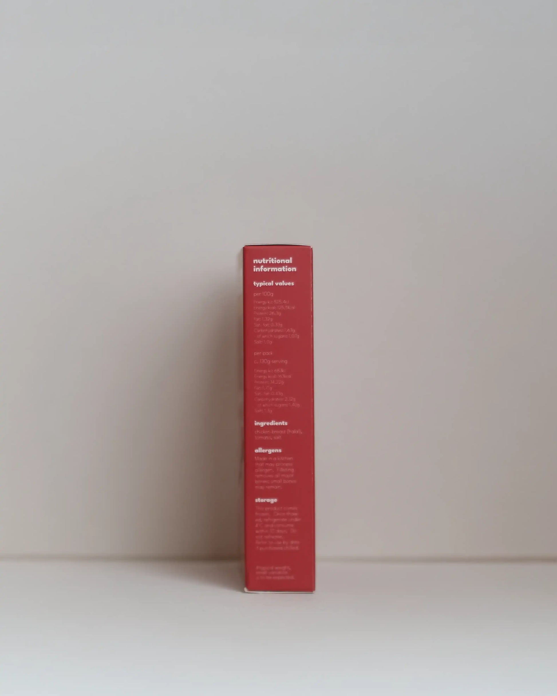 Side view of a SousFeed tomato bomb flavoured chicken breast and its packaging on a white background